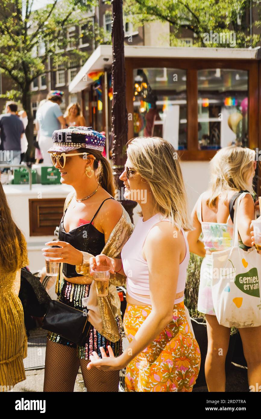 Amsterdam, Nordholland, Niederlande – 6. August 2022: Zwei junge Frauen, die Pride Amsterdam feiern, gehen in bunten Outfits durch die Straße Stockfoto