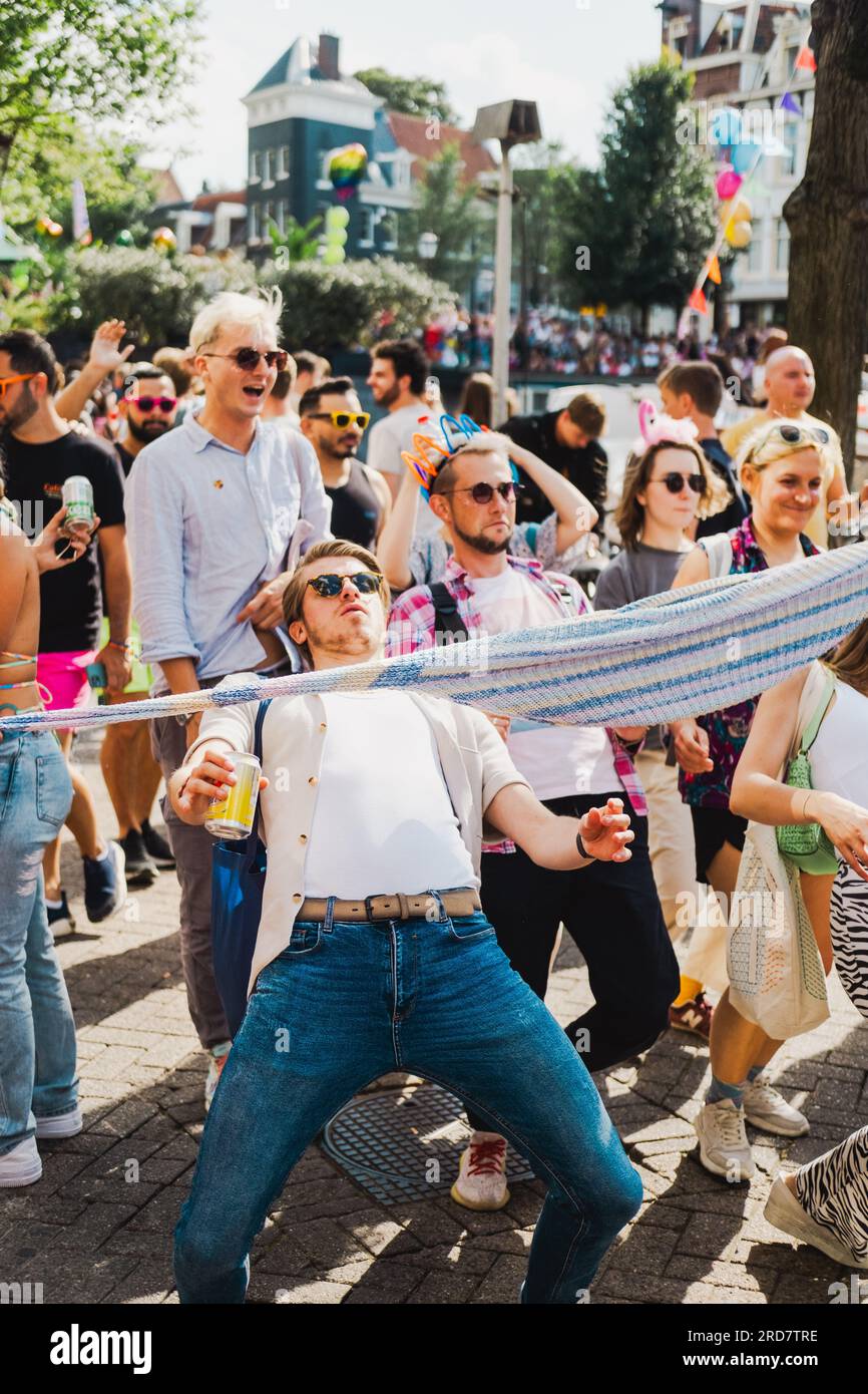 Amsterdam, Nordholland, Niederlande – 6. August 2022: Ein junger Mann in der Mitte der Menge feiert die Pride Amsterdam Parade und macht improvisierte Limbo Dan Stockfoto