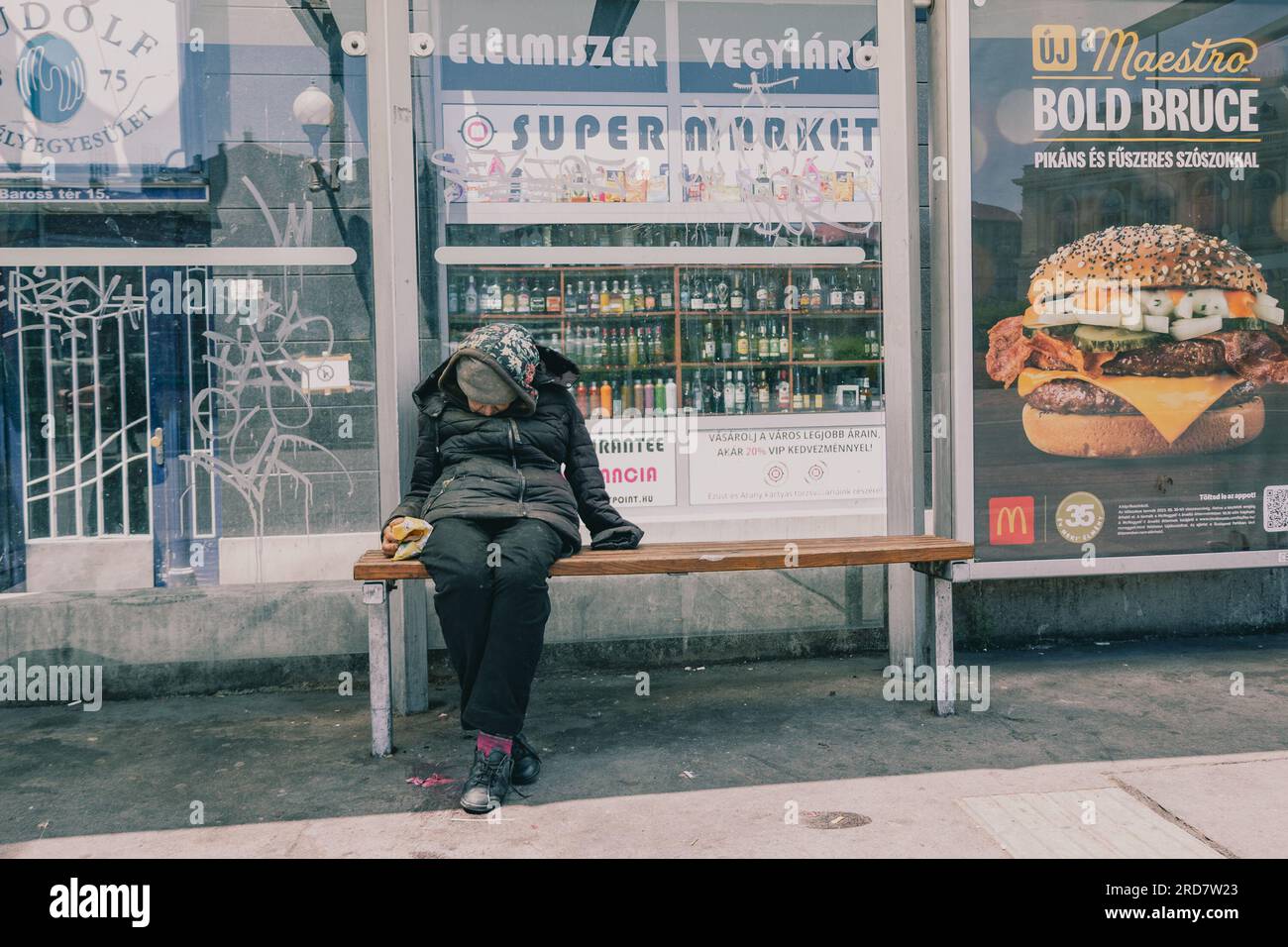 11. Juni 2023, Budapest, Ungarn: Eine obdachlose Frau, die auf einer Bank sitzt. In Ungarn, insbesondere in Budapest, herrscht anhaltende Besorgnis über Obdachlosigkeit. Aufgrund der hohen Inflation ist die Zahl der Menschen, die auf den Straßen leben, in der Stadt gestiegen. Faktoren wie Armut, Arbeitslosigkeit, psychische Gesundheit und Mangel an bezahlbarem Wohnraum tragen zu dem Problem bei. Die ungarische Regierung und die lokalen Behörden haben verschiedene Maßnahmen zur Bekämpfung der Obdachlosigkeit ergriffen. Dazu gehören die Bereitstellung von Notunterkünften, Sozialdiensten und Programmen zur Wiedereingliederung in Stockfoto