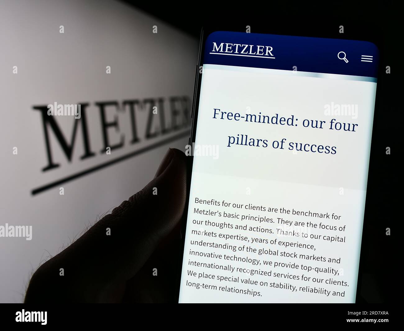 Person, die ein Mobiltelefon mit der Webseite der Bankgesellschaft B. Metzler seel besitzt. Sohn Co AG auf Bildschirm mit Logo. Konzentrieren Sie sich auf die Mitte des Telefondisplays. Stockfoto