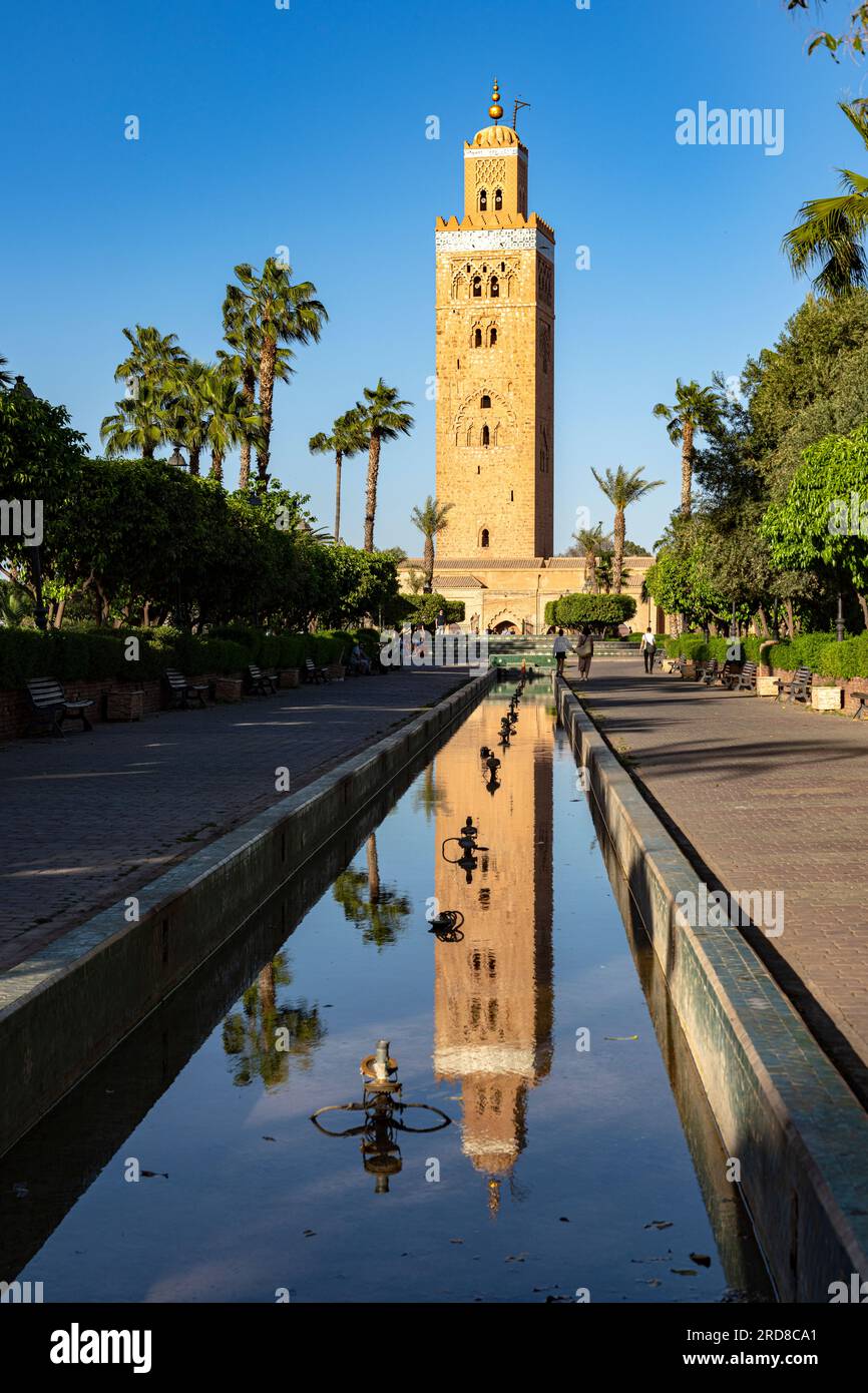 Antiker Minarettturm der Koutoubia-Moschee, UNESCO-Weltkulturerbe, reflektiert im Wasser in einem palmengesäumten Park, Marrakesch, Marokko Stockfoto