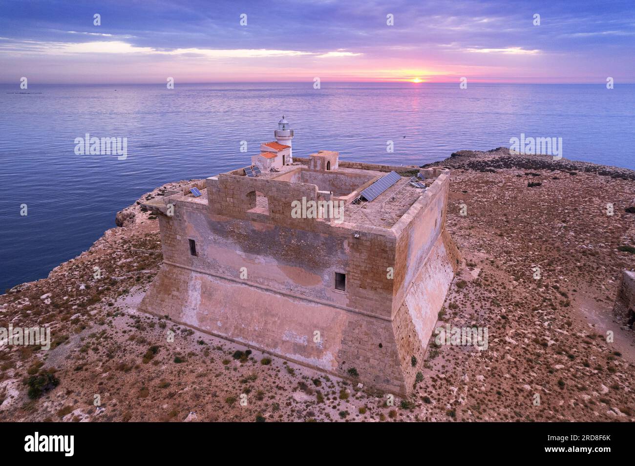 Luftaufnahme des befestigten Turms mit dem Leuchtturm, der bei Sonnenaufgang auf der Insel Capo Passero erbaut wurde, Insel Capo Passero Stockfoto