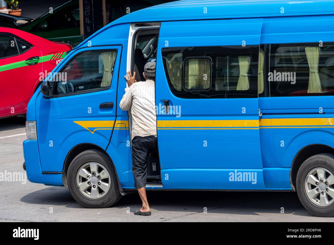 Ein Mann steigt aus dem Kleinbus - Gemeinschaftstaxi, ein traditioneller öffentlicher Nahverkehr für Menschen in Thailand Stockfoto