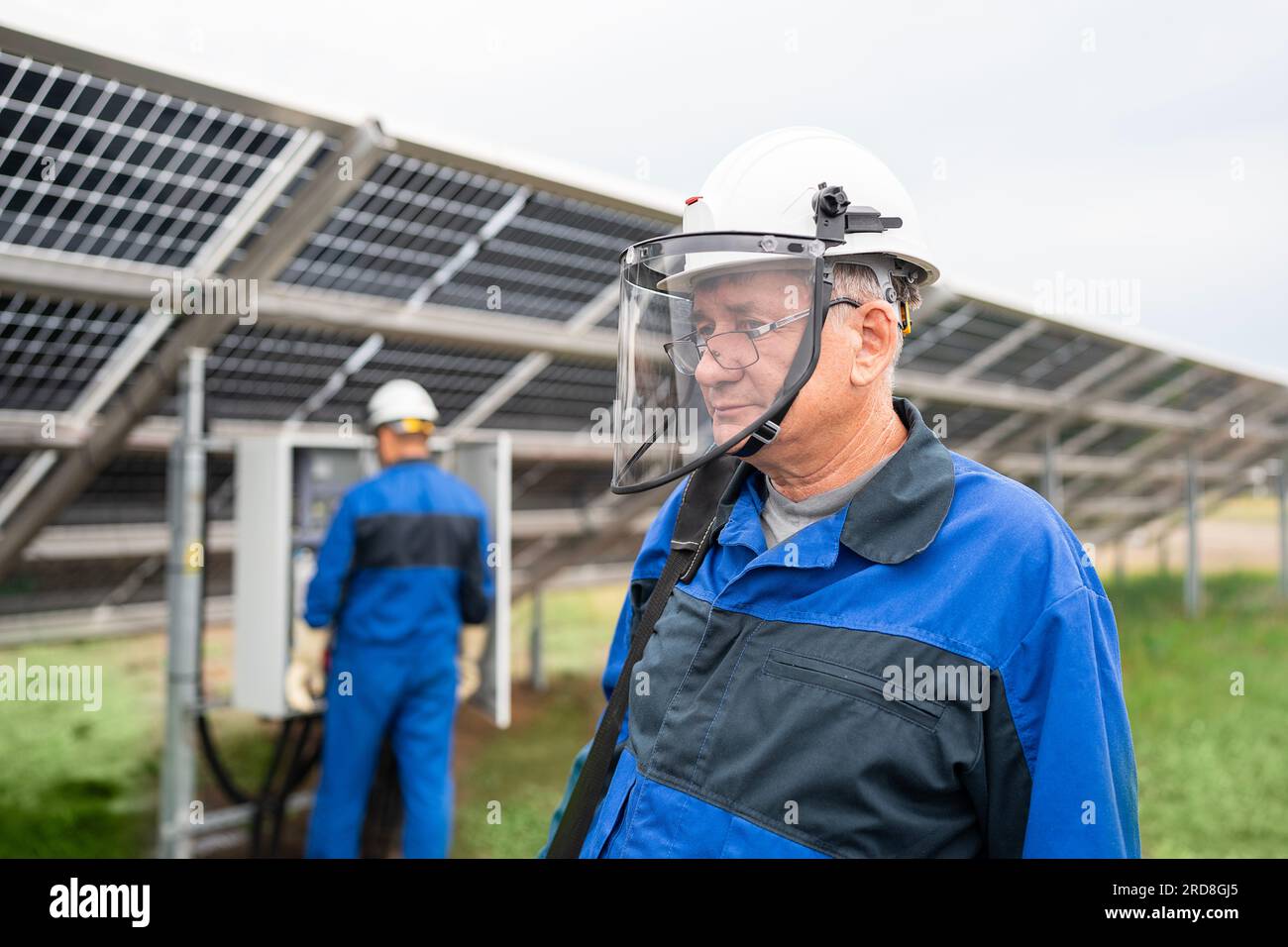 Ein erfahrener Servicetechniker steht vor Solarpaneelen. Techniker warten Solarzellen im Solarenergiewerk unter Morgensonne Stockfoto
