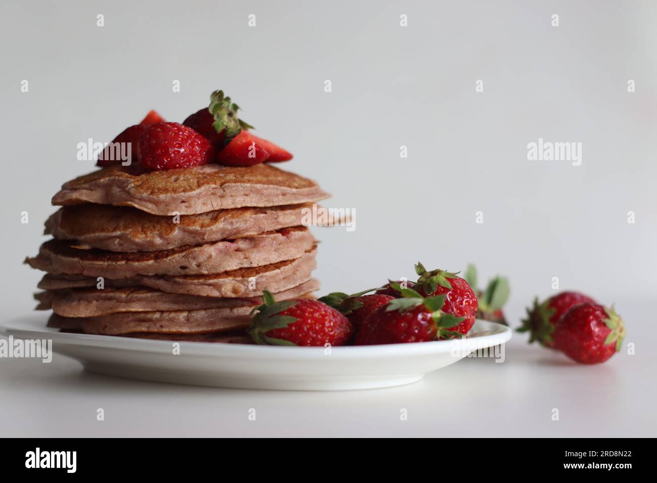 Buttermilch-Erdbeerpfannkuchen. Eine fröhliche Version von Pfannkuchen mit Erdbeersauce und frisch geschnittenen Erdbeeren, die dem Pfannkuchenteig hinzugefügt wurden. Auf Peitsche geschossen Stockfoto