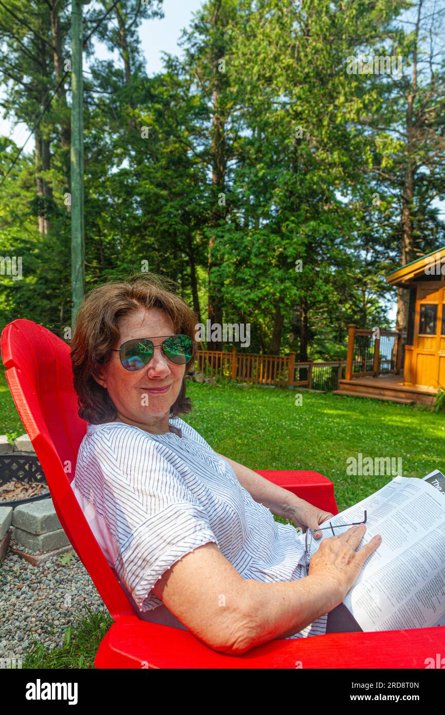 Junge Großmutter, die eine Zeitschrift liest und sich am Sparrow Lake Muskoka Ontario Canada entspannen kann Stockfoto