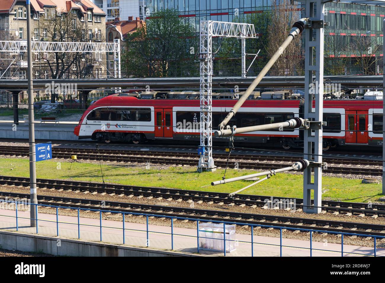 Poznan, Polen - 21. April 2023: Moderner weißer und roter Regionalzug der Wielkopolska Railway fährt in Richtung Bahnhof. Blick von oben. Stockfoto