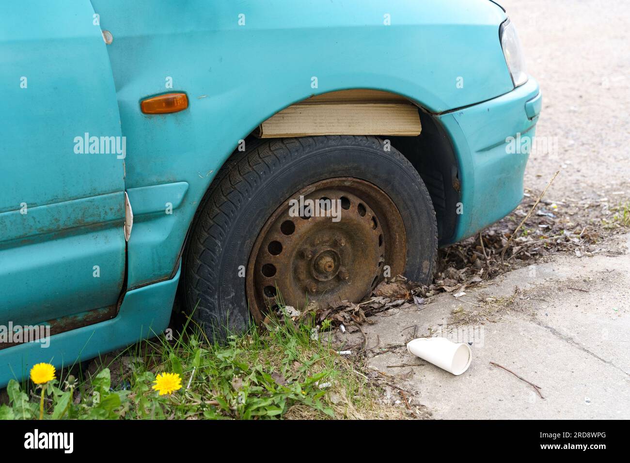 Auf der Straße steht ein altes blaues unbenutztes Auto mit einem Platten Reifen. Nahaufnahme. Stockfoto
