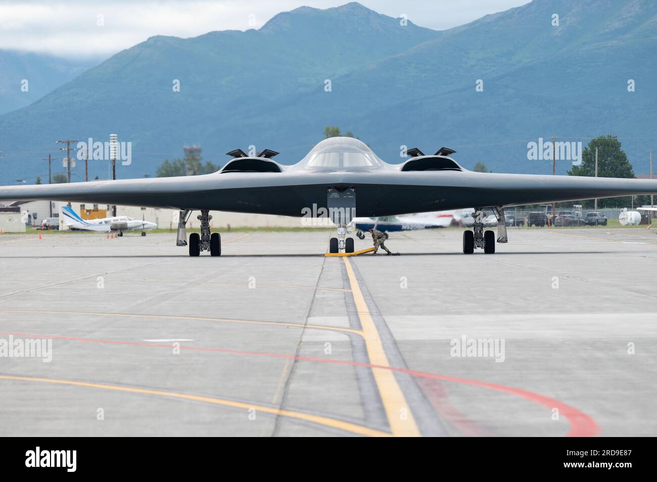 USA Air Force Airman, der dem 509. Bombenflügel zugeteilt ist, entfernt den Keil, bevor der B-2 Spirit am Joint Base Elmendorf-Richardson, Alaska, 19. Juli 2023 startet. Mit den Missionen der Bomber-Task Force können die Crews einen hohen Stand der Einsatzbereitschaft und Leistungsfähigkeit aufrechterhalten und ihre stets einsatzbereite, globale Angriffsfähigkeit validieren. (USA Air Force Foto von Sheila deVera) Stockfoto