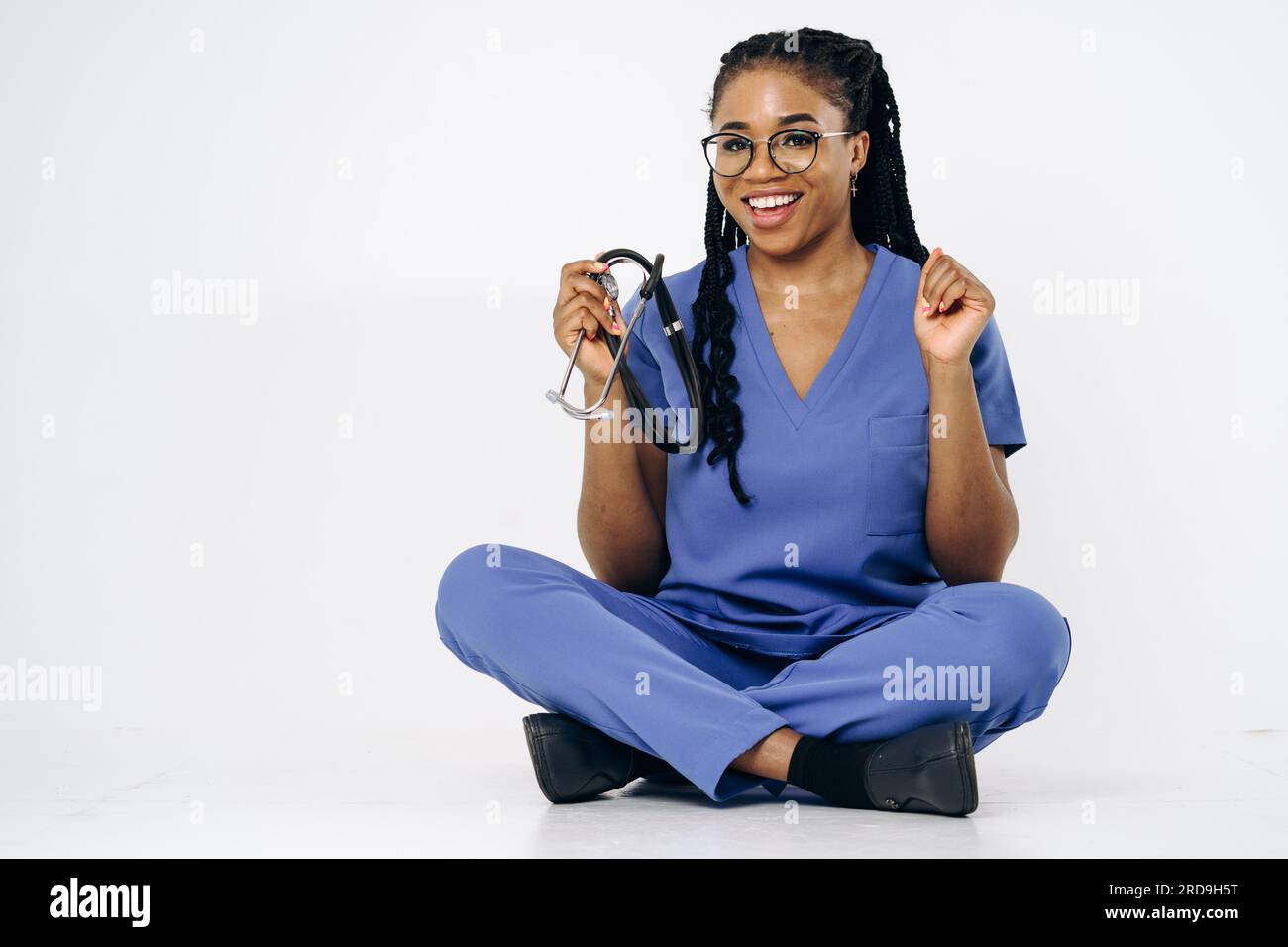 Porträt einer lächelnden Krankenschwester oder Ärztin in blauen Bürsten Uniform sitzendes Stethoskop Stockfoto
