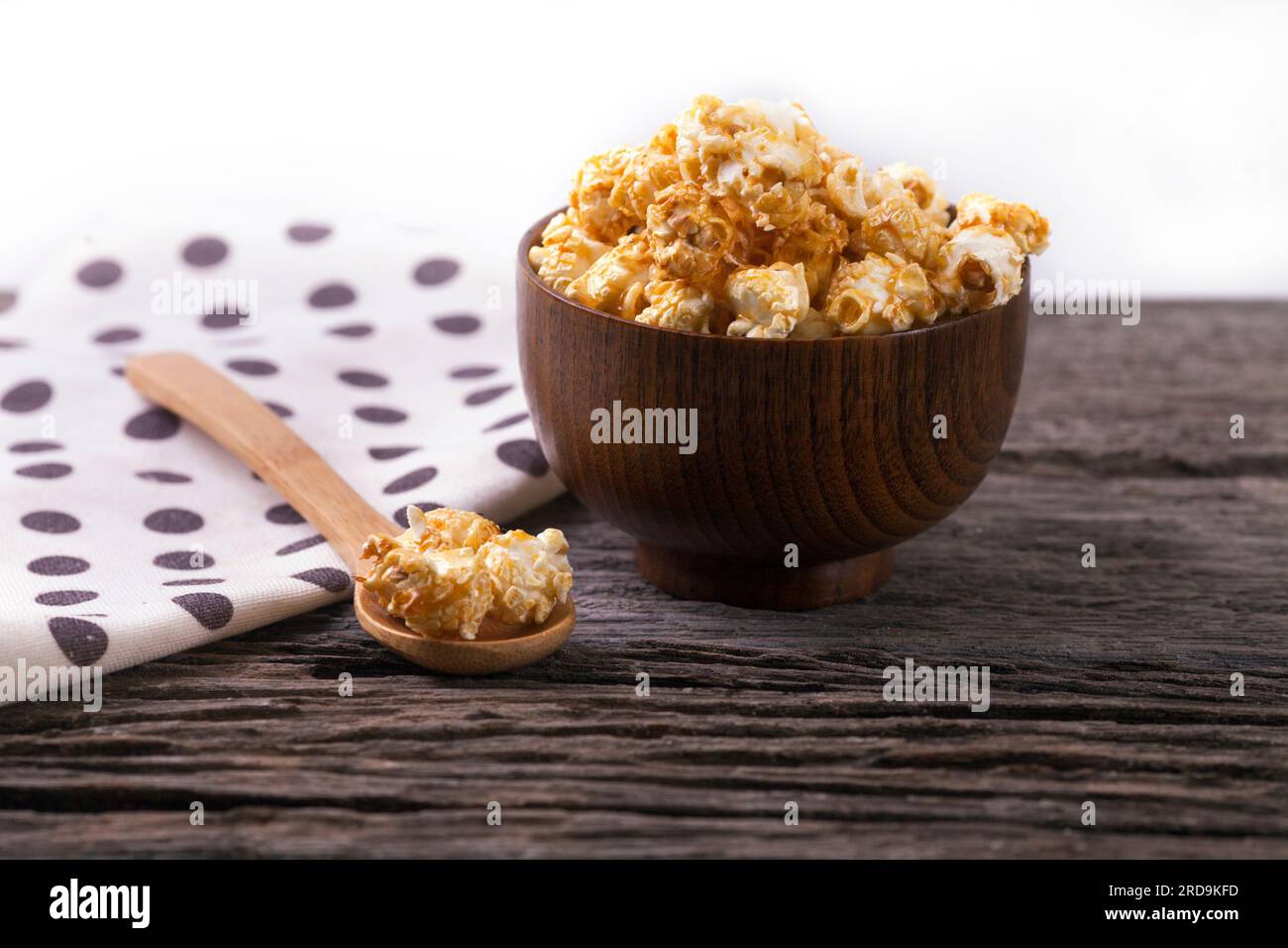 Karamell-Popcorn in der Schale hölzerner weißer Hintergrund. Stockfoto