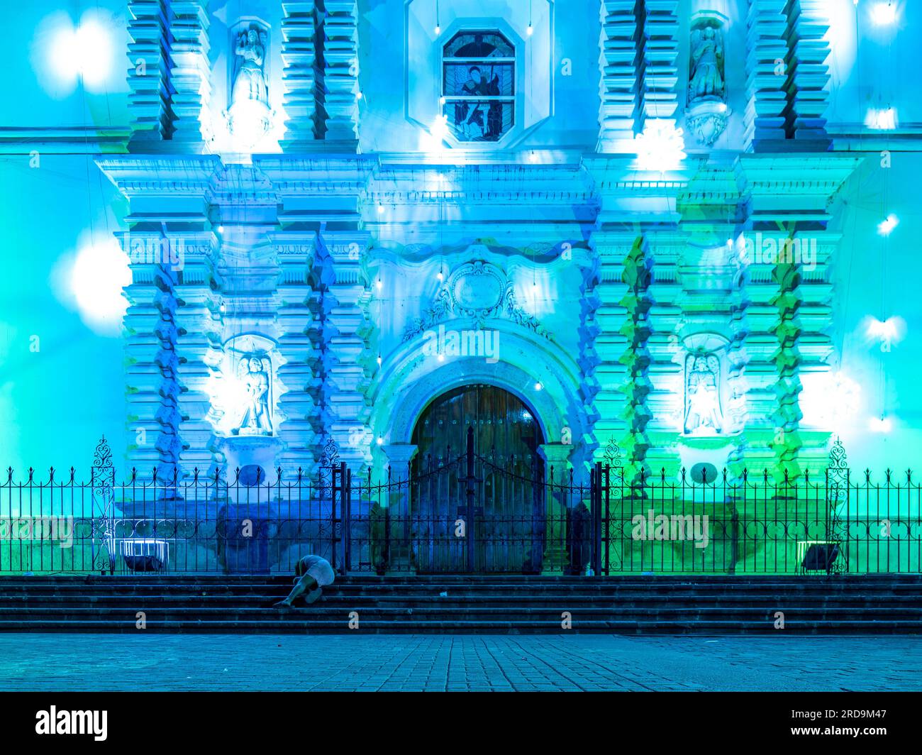 Tegucigalpa, Francisco Morazan, Honduras - 11. Dezember 2022: Hauptfassade der Kathedrale von Tegucigalpa bei Nacht beleuchtet von blauen und grünen Lichtern mit Woman Sleep Stockfoto