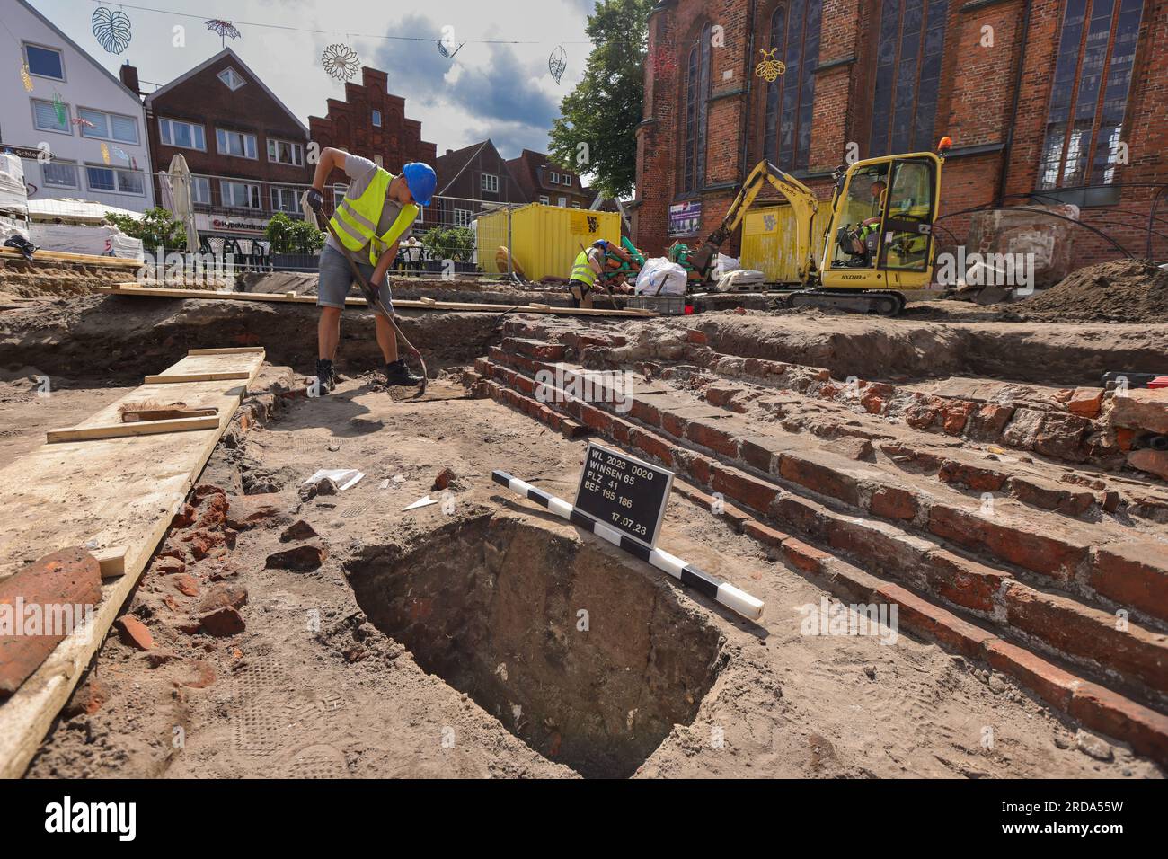 Winsen, Deutschland. 17. Juli 2023. Mitarbeiter des Archäologischen Museums Hamburg graben auf dem Kirchenvorplatz St. Marienkirche in Winsen/Luhe (Bezirk Harburg). Bevor im Rahmen des Stadterneuerungsprojekts „Winsen 2030“ ein Wasserspiel errichtet wird, wird hier die Baugeschichte entziffert. Seit dem Mittelalter befinden sich das Rathaus und ein städtischer Glockenturm an diesem Standort. (Zu dpa: „Like a Puzzle“ – Sonderausgrabungen im Stadtzentrum von Winsen“) Kredit: Ulrich Perrey/dpa/Alamy Live News Stockfoto