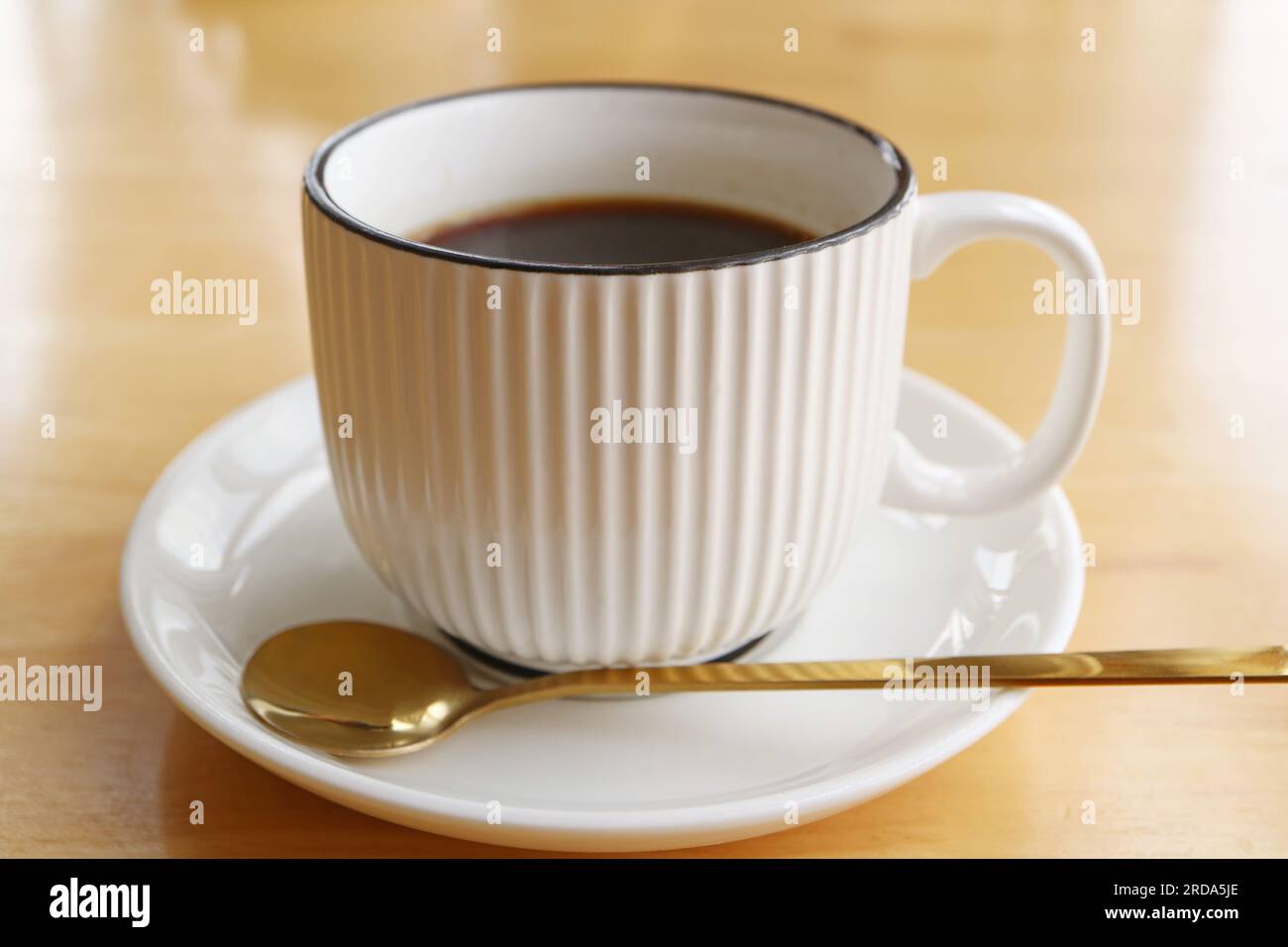 Tasse schwarzen Kaffee mit Löffel isoliert auf einem Holztisch Stockfoto