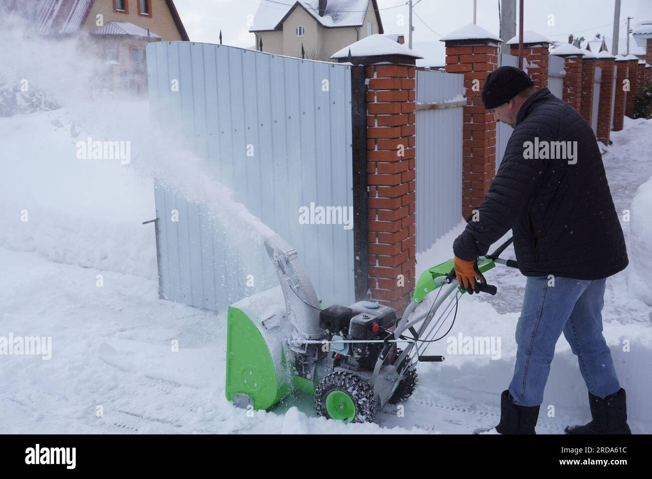 Ein Mann reinigt Schnee im Winter im Hof des Hauses, ein Mann reinigt  Schnee mit einer Schneefräse Stockfotografie - Alamy