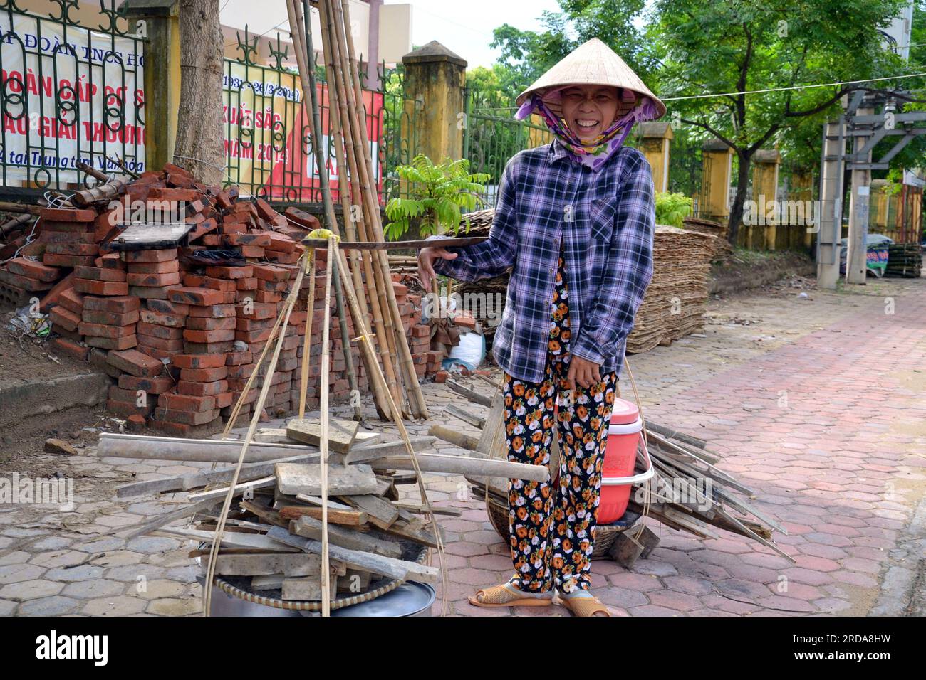 Ha Tinh, Vietnam, 2014, eine Frau ruht sich aus, wenn sie eine schwere Last trägt, mit einer traditionellen Methode, bei der sie zwei Körbe über die Schulter trägt Stockfoto