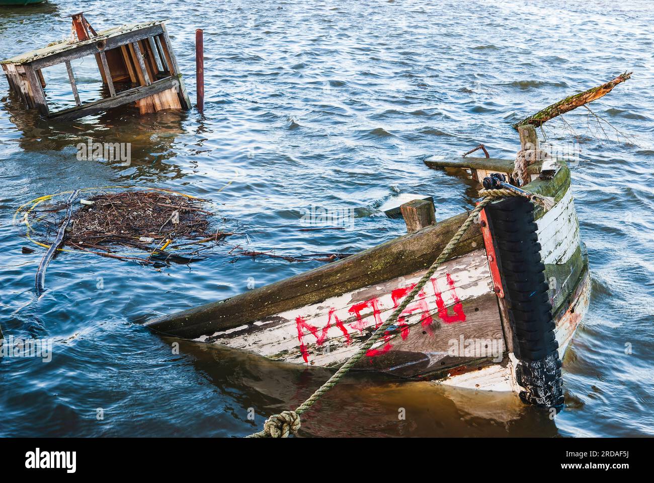 Ein gesunkenes Schiffswrack liegt auf dem Grund eines friedlichen Hafens, dessen Rumpf im sonnigen Meer schimmert. Stockfoto