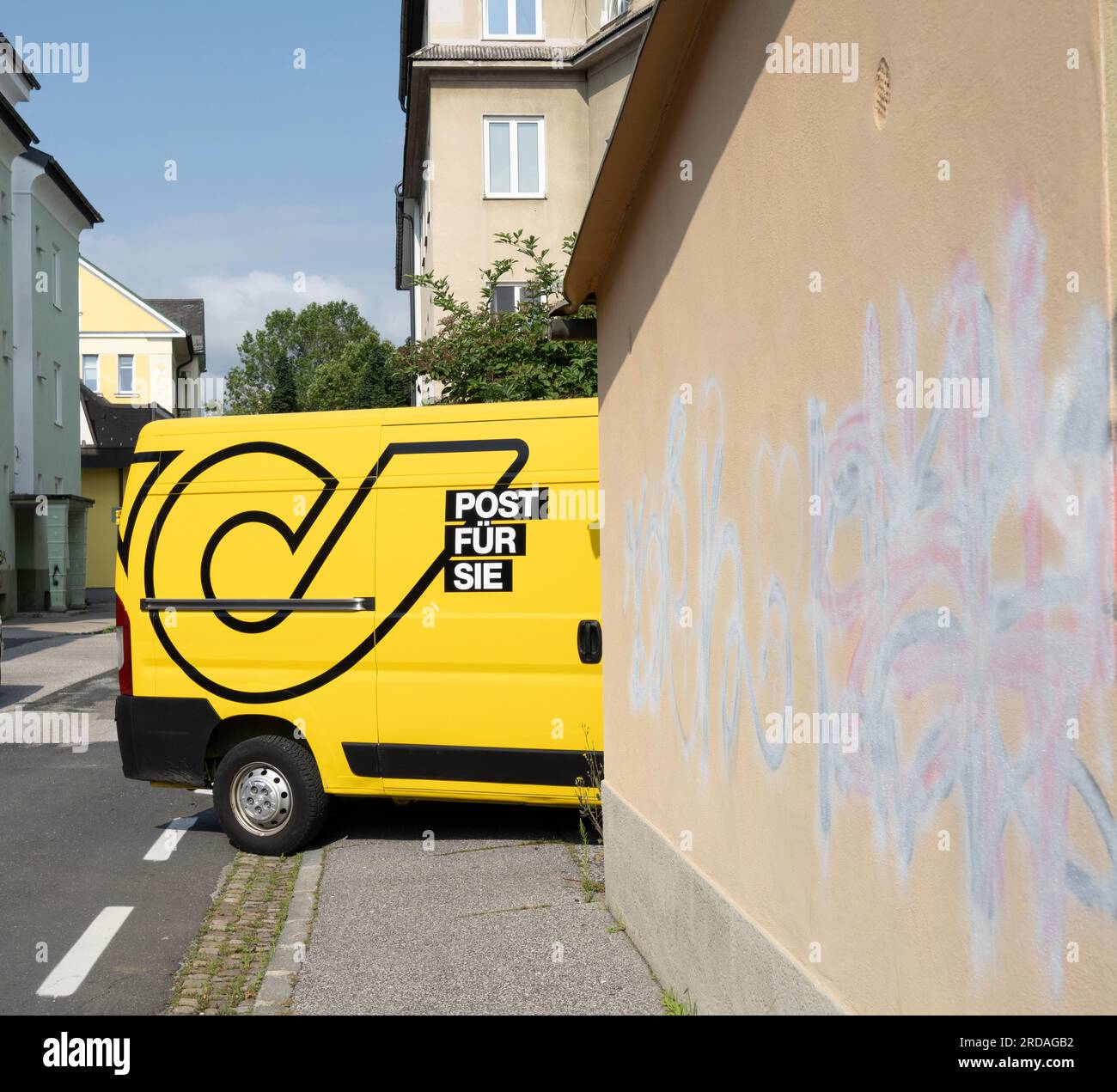 Villach, Österreich. Juli 18 2023. Der österreichische Postwagen befindet sich im Innenhof eines Apartmentgebäudes im Stadtzentrum Stockfoto