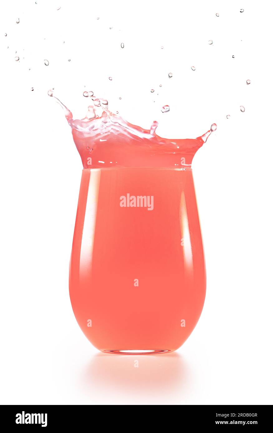 Rosafarbener Saft, der aus überfließendem, auf weißem Hintergrund isoliertem Trinkglas spritzt. Erfrischender gesunder Mocktail. Stockfoto