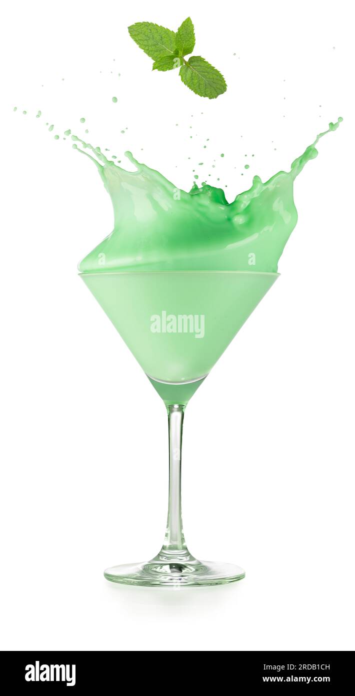 Minzeblätter fallen in einen spritzernden Heuschrecken-Cocktail, der in einem martini-Becher serviert wird, isoliert auf weißem Hintergrund. Ein richtiger Schuss. Stockfoto