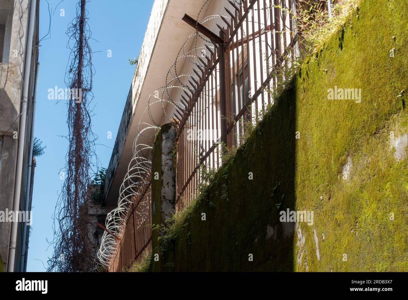 Metallzäune und Stacheldraht über einer Betonwand außerhalb eines geschlossenen Werks Indien Stockfoto