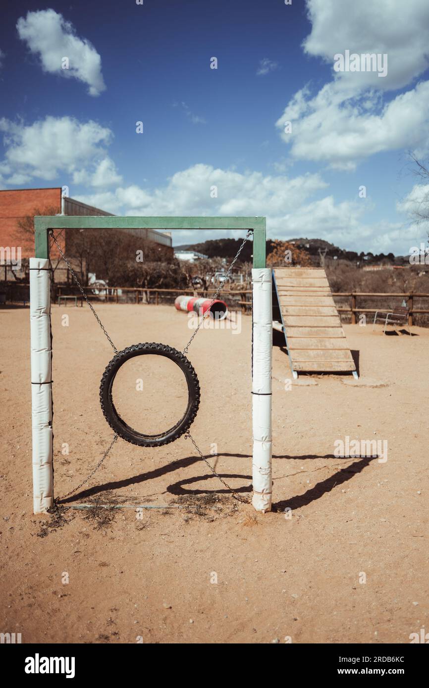 Ein vertikaler Schuss in Barcelona, ein Hundepark mit sandigem Boden und Ausrüstung für Beweglichkeitstraining. Ein Hundesprung-Reifen und eine hölzerne Rampe im Hintergrund Stockfoto