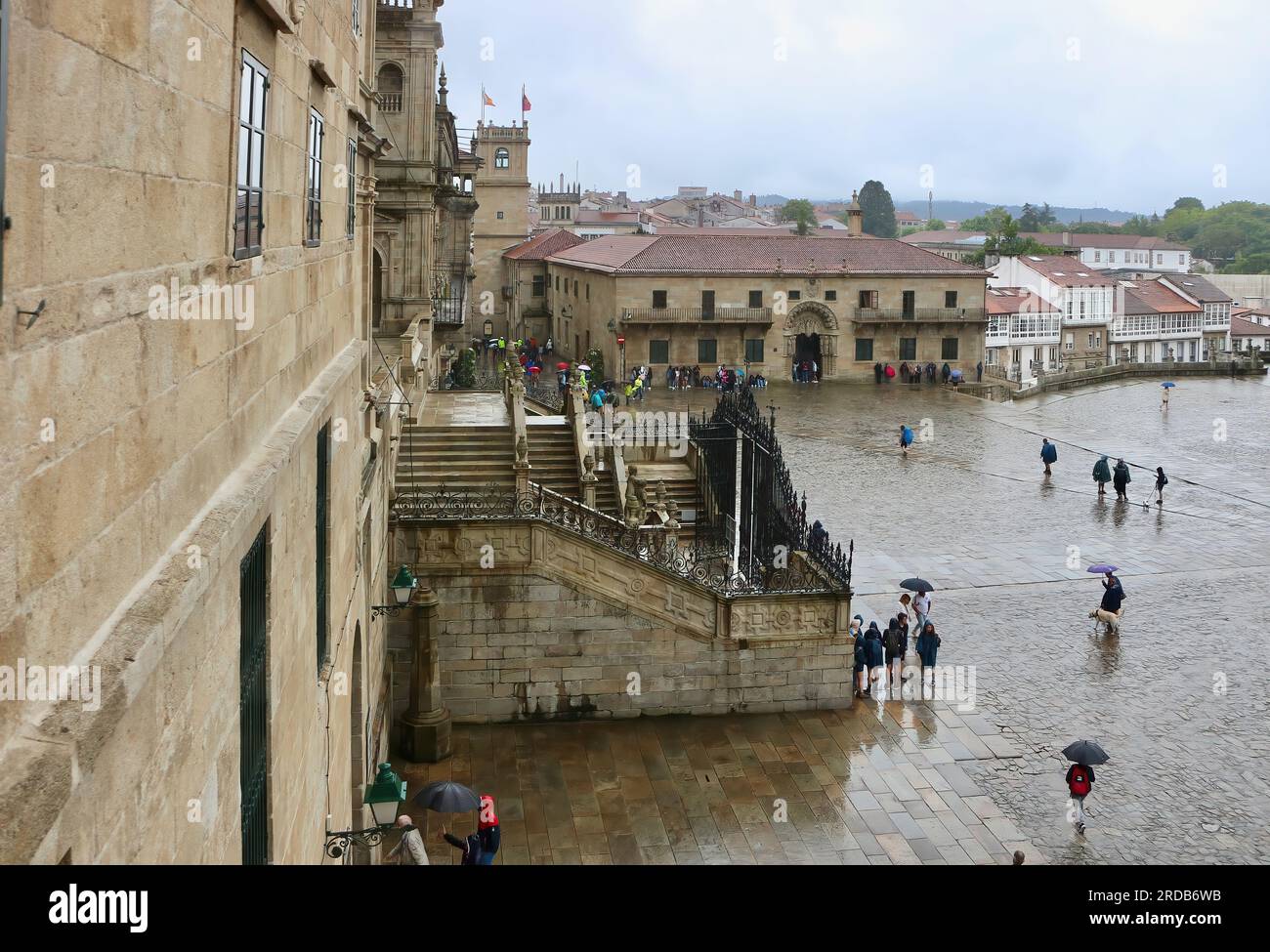 Die mit Stein gepflasterte Plaza de Obradoiro, von oben gesehen an einem regnerischen Juni-Tag mit Touristen, die mit Plastiktüchern unterwegs sind Santiago de Compostela Galicia Spanien Stockfoto