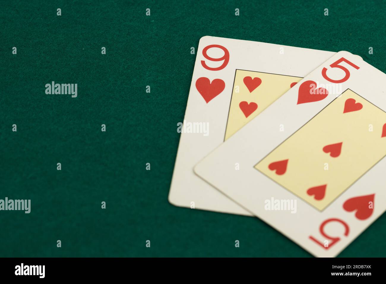 Vervollständigung von zwei Spielkarten vom französischen Deck (9 und 5 der Herzen) und auf einem grünen Baize mit Copyspace Stockfoto