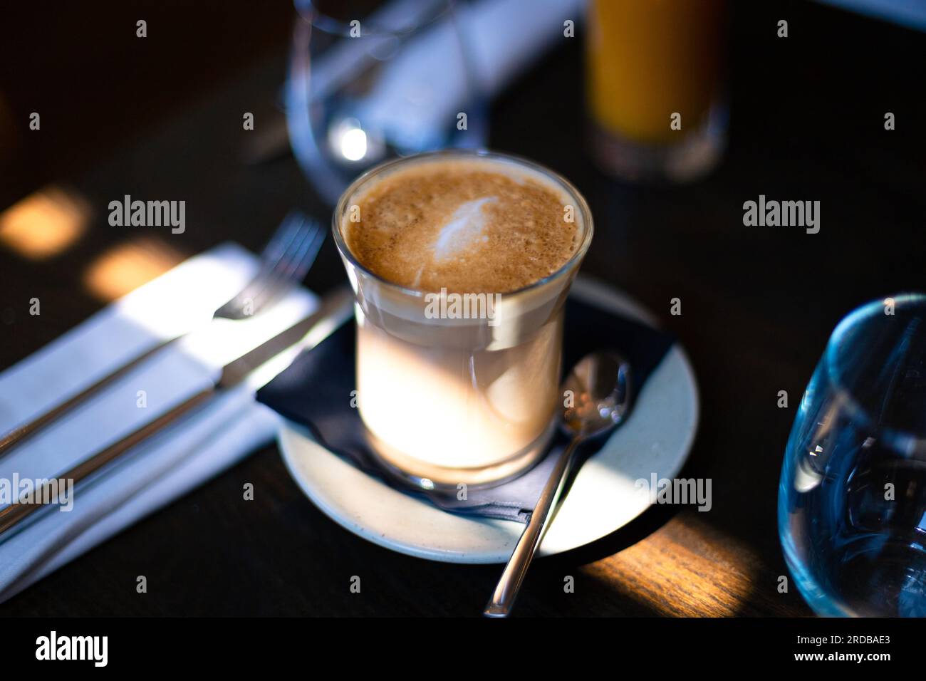 Latte-Kaffee in einem Glasbecher an einem Sonntagmorgen in einem Restaurant Stockfoto