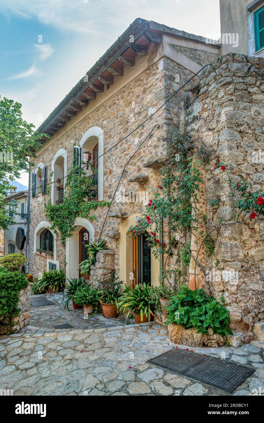 Enge Straße im Valldemossa mit vielen allgegenwärtigen Blumen. Architektonische Schätze - der Zauber von Valldemossas historischem Zentrum und seinem Mittelmeer Stockfoto