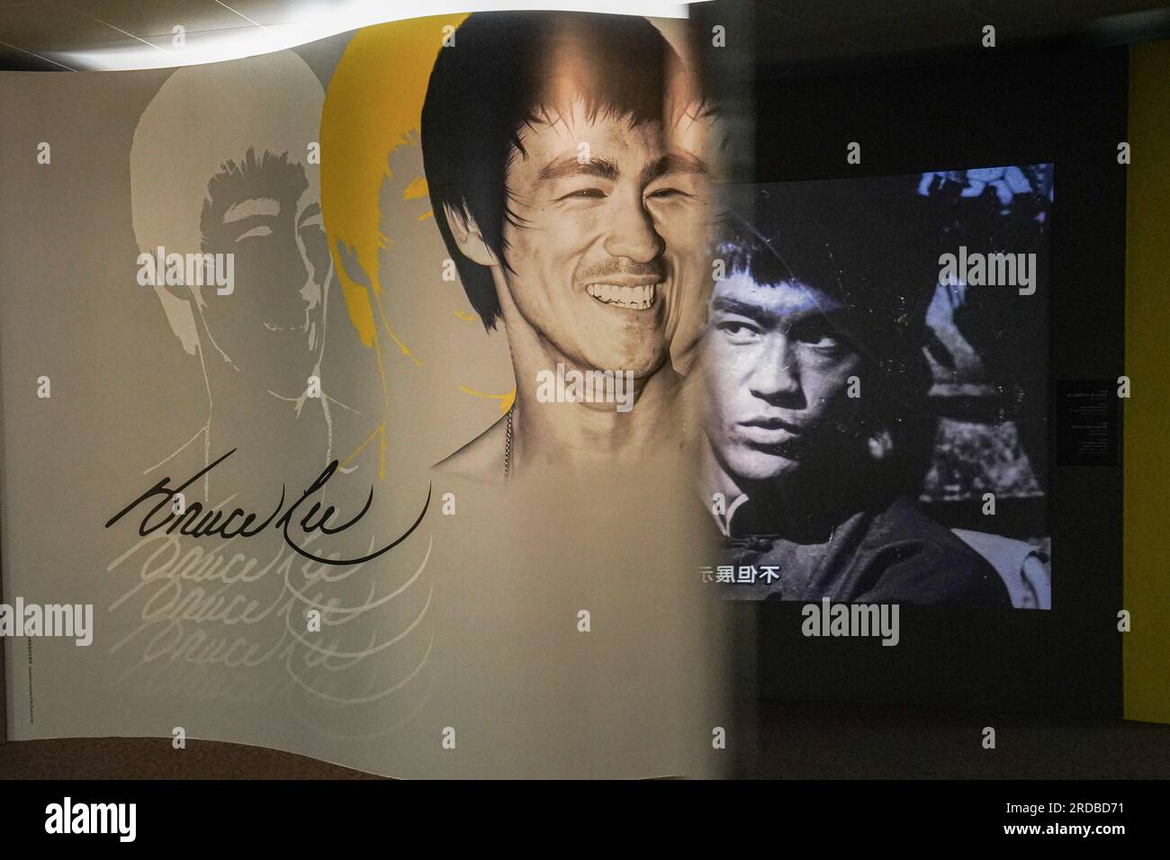 Riesige Poster von Bruce Lee sind in der Ausstellung zu sehen. Die Regierung Hongkongs feiert den 50. Todestag des Kampfkünstlers Bruce Lee mit einer bedeutenden Ausstellung im Hong Kong Heritage Museum. Die Ausstellung zieht Hunderte von Besuchern an und zollt dem Leben und Vermächtnis des legendären Kampfkünstlers Tribut und fasziniert die Besucher mit Ausstellungen, die seine außergewöhnlichen Leistungen und seinen kulturellen Einfluss zeigen. Gleichzeitig gehen einige Leute zur Statue von Bruce Lee in Tsim Sha Tsui und ehren sein Andenken mit herzlichen Gesten und Erinnerungen. Stockfoto