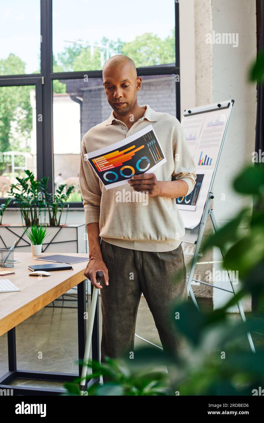 Vielfalt und Integration, echte Menschen, mutiger afroamerikanischer Mann mit Myasthenia gravis, dunkelhäutiger Büroangestellter, der mit einem Gehstock steht und hält Stockfoto