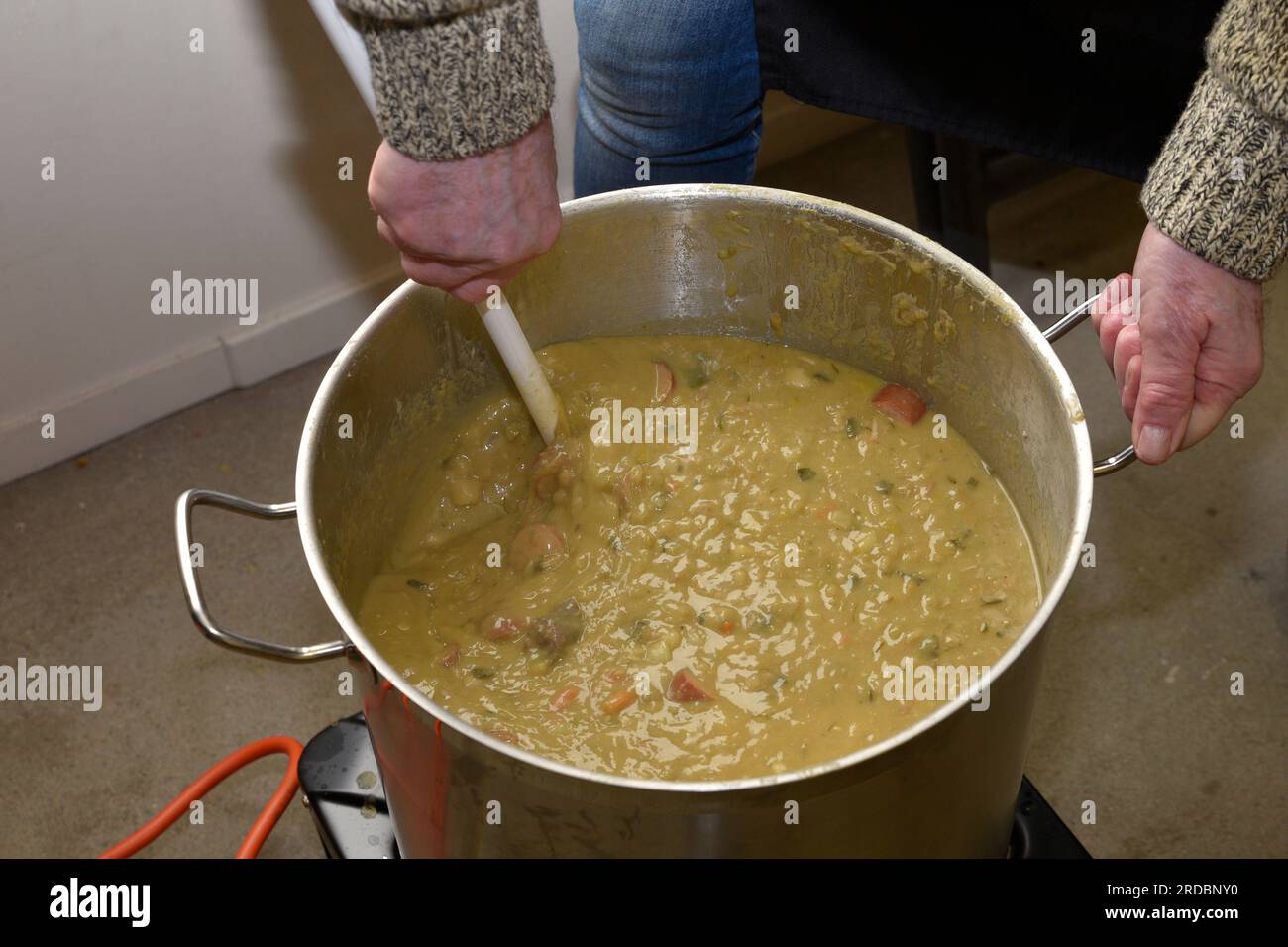 Rühren in einem großen Topf gefüllt mit holländischer Erbsensuppe. Stockfoto