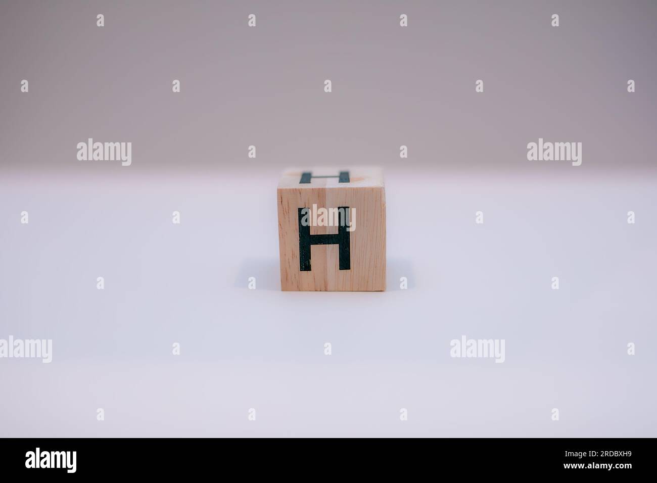 Holzblock mit der Aufschrift „H“ auf weißem Hintergrund. Stockfoto