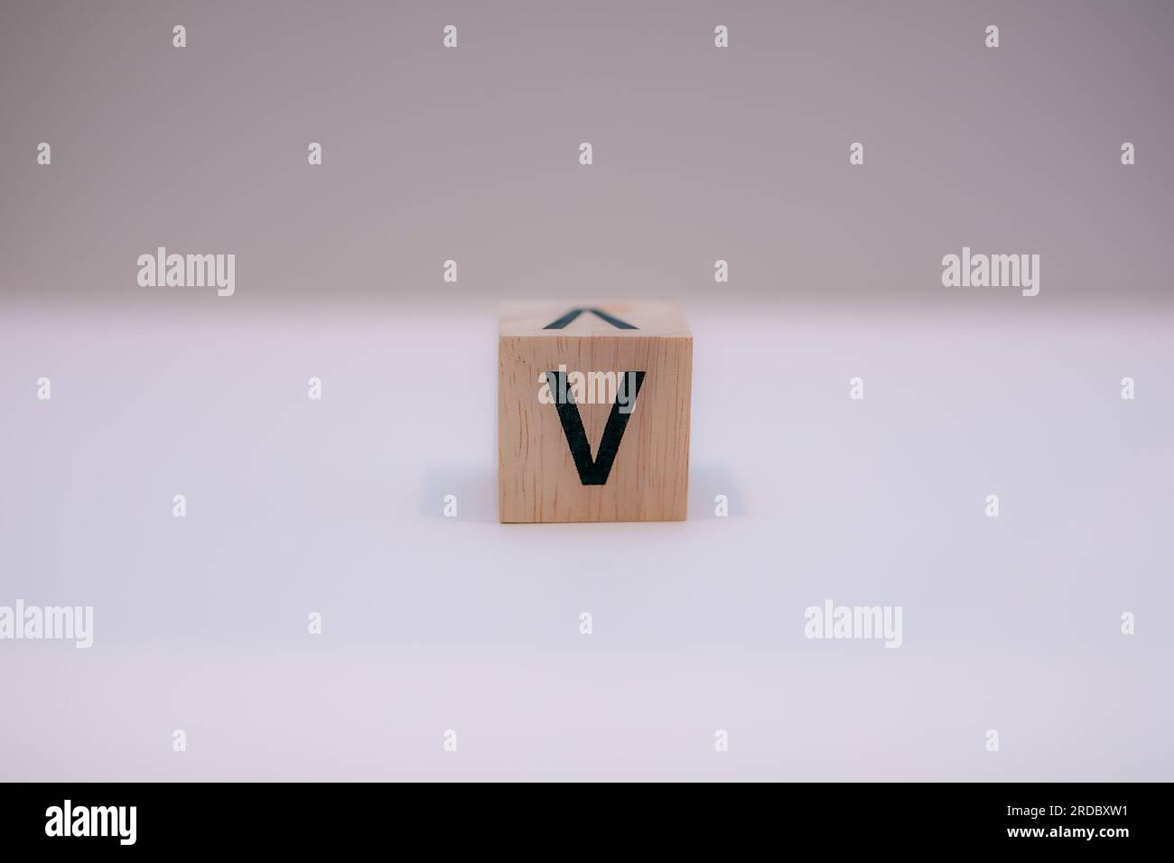 Holzblock mit der Aufschrift „V“ auf weißem Hintergrund. Stockfoto
