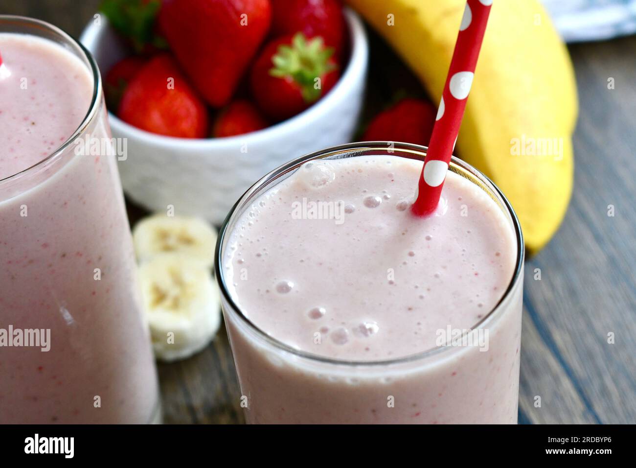 Erdbeerbananen-Smoothie in einem durchsichtigen Glas auf einer rustikalen Oberfläche Stockfoto