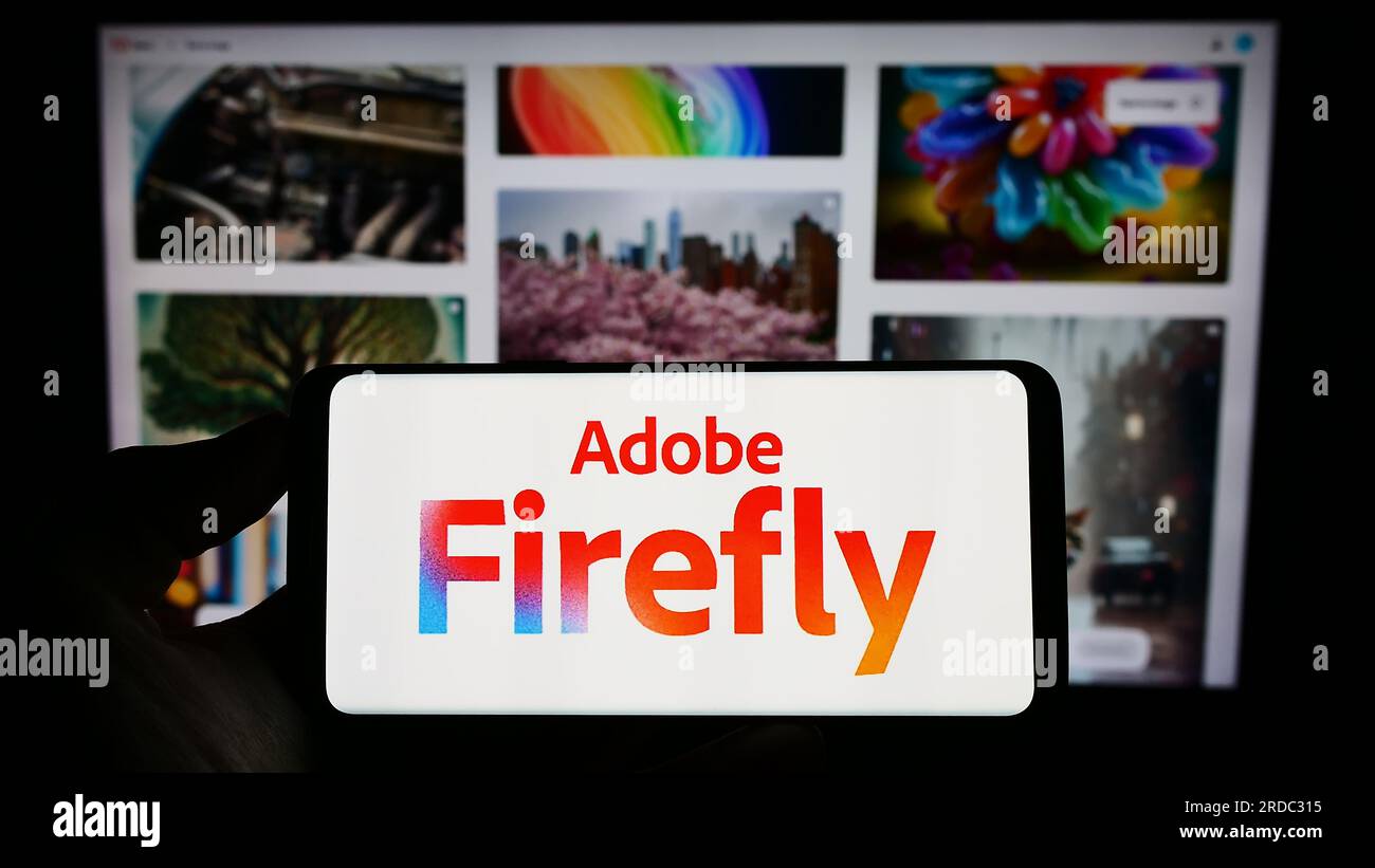 Person, die ein Mobiltelefon mit dem Logo des generativen KI-Produkts Adobe Firefly auf dem Bildschirm vor der Unternehmenswebseite hält. Konzentrieren Sie sich auf das Display des Telefons. Stockfoto