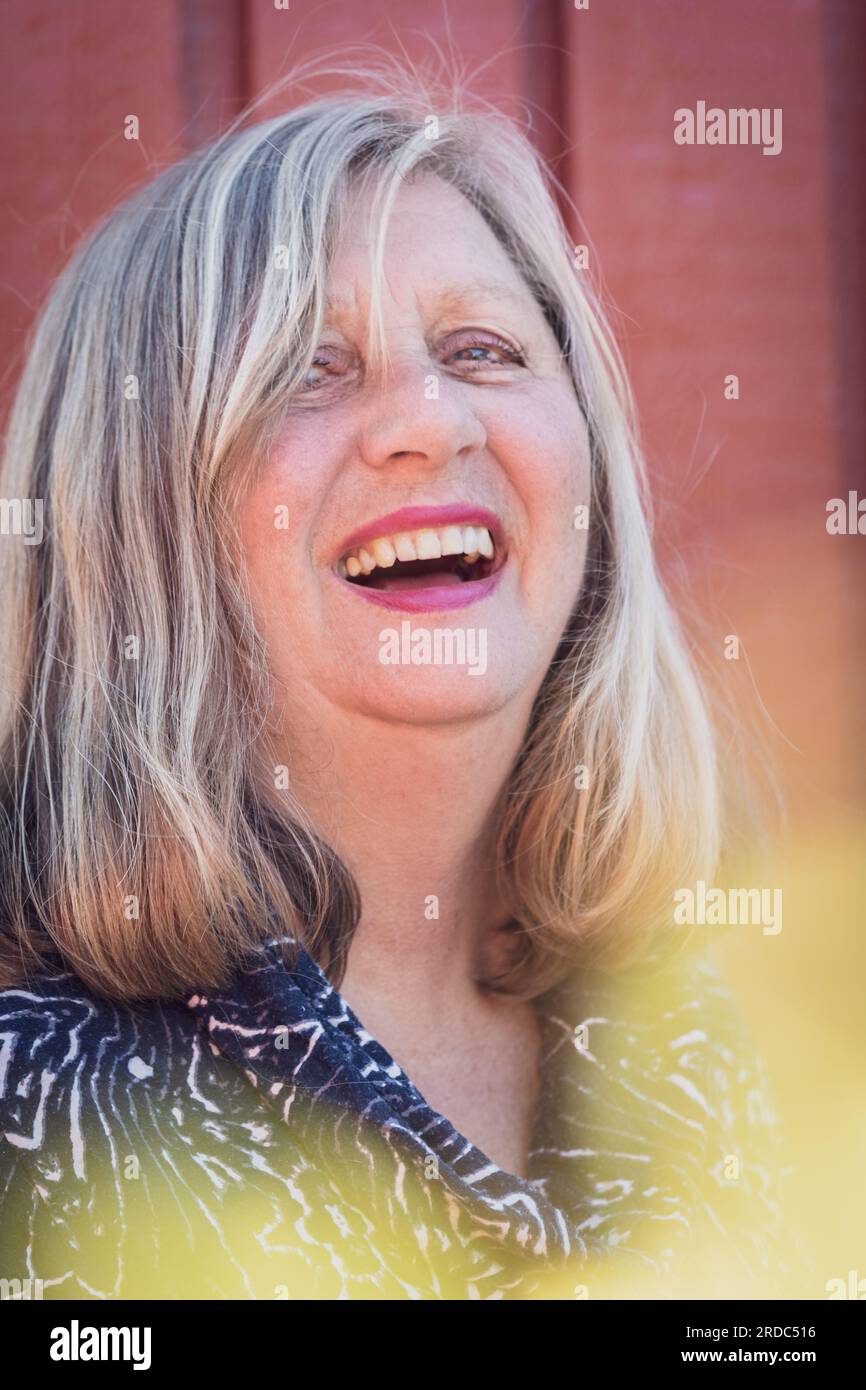 Gelegenheitsporträt einer blonden haarigen, offenen und lachenden älteren Frau Stockfoto