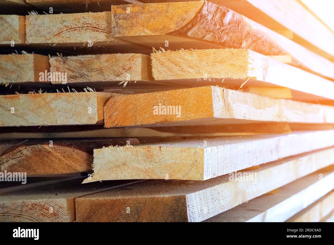 Neue gehobelte Holzbretter im Sägewerk gestapelt. Beschaffung und Verkauf von Baumaterial. Trockenes Holz. Holzbearbeitung. Hintergrund. Stockfoto