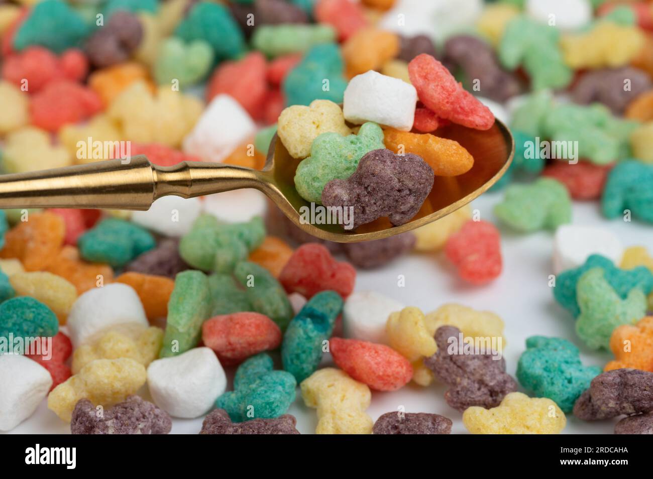 Bunte Cornflakes in der Makronahansicht mit goldenem Löffel Stockfoto