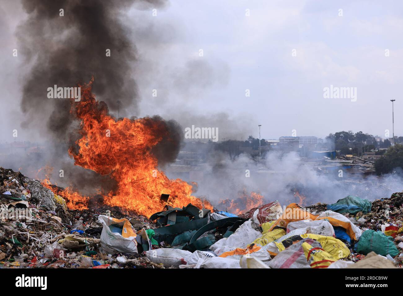 Das Feuer brennt, um Müll auf der Dandora-Mülldeponie zu verbrennen. Die Regierung des Stadtbezirks Nairobi plant die Errichtung einer Recyclinganlage, die die auf der Deponie Dandora abgelagerten Abfälle in Energie umwandeln wird. Die weitläufige Mülldeponie nimmt täglich etwa 2.000 Tonnen Abfall auf, was sie zur geschäftigsten Arbeitsstätte für Abfallsammler macht, um Kunststoffe und andere recycelbare Materialien zu finden. Stockfoto