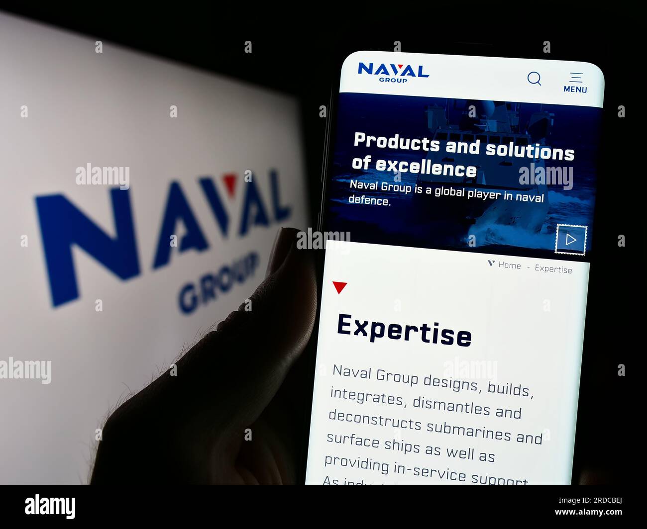 Person, die ein Handy mit einer Webseite der französischen Verteidigungsfirma Naval Group S.A. auf dem Bildschirm vor dem Logo hält. Konzentrieren Sie sich auf die Mitte des Telefondisplays. Stockfoto