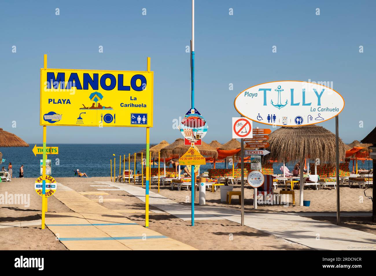Liegen und Sonnenschirme am Touristenstrand des beliebten mediterranen Resorts La Carihuela in Torremolinos. Stockfoto