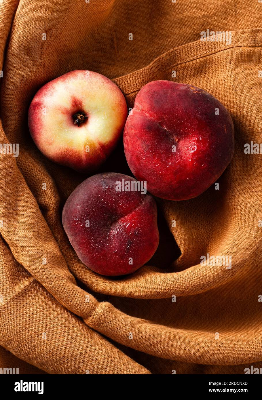 Reife und frische flache Pfirsiche auf einem Leinentuch. Ernte. Obstladen Stockfoto