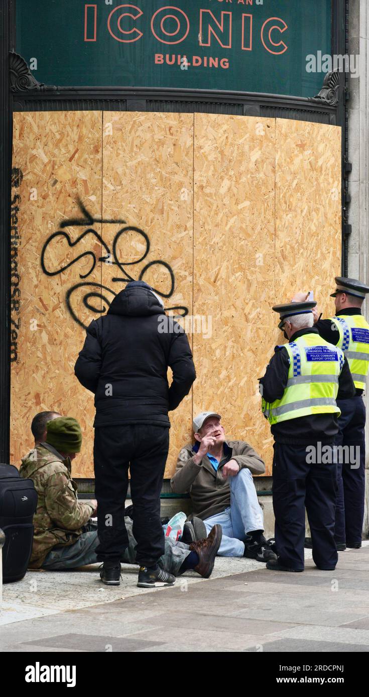 Zwei Polizisten unterhalten sich mit einer Gruppe Obdachloser, die in der Tür eines leeren Kaufhauses von Howells geschlafen haben Stockfoto