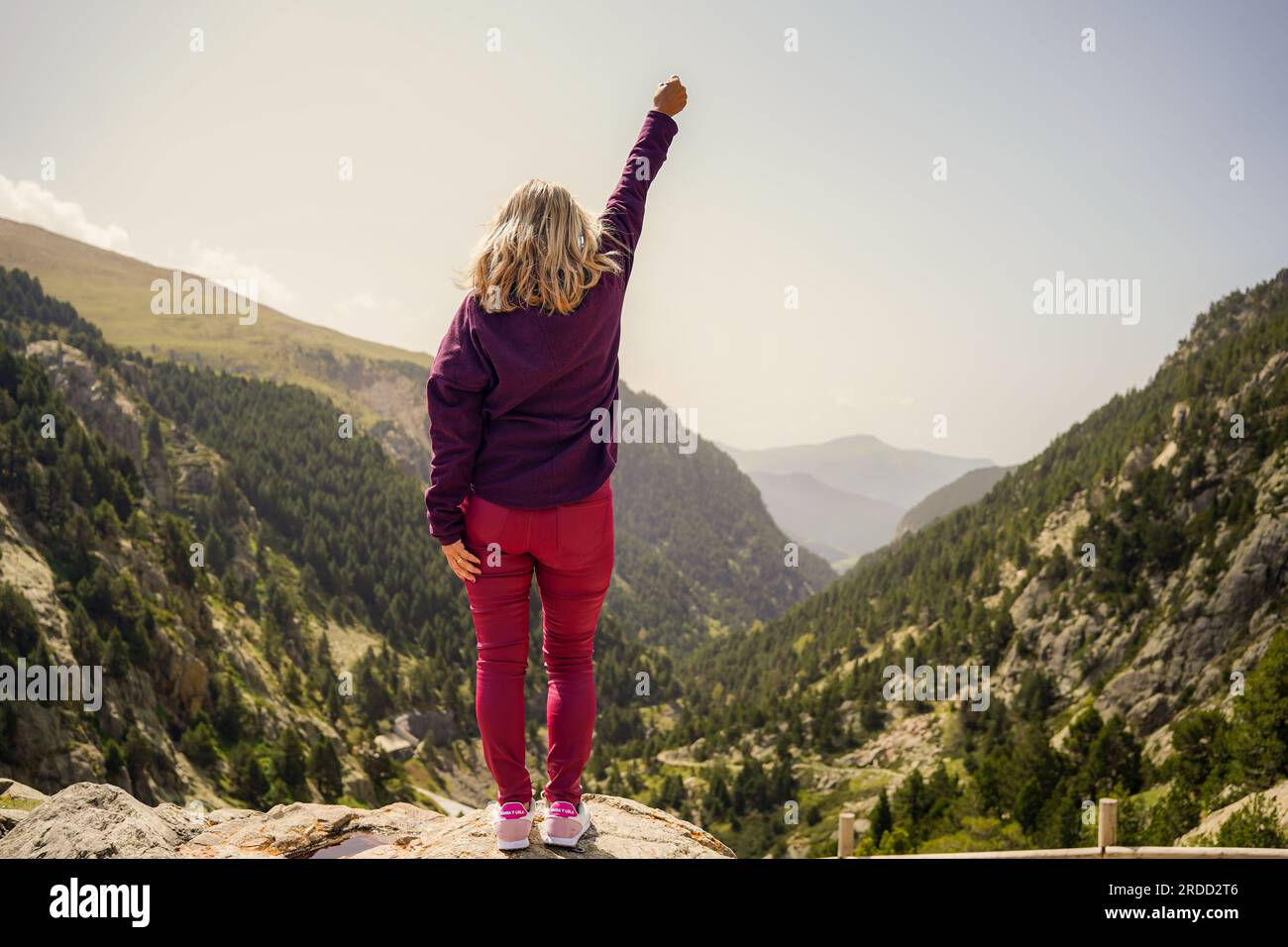 Eine mächtige ältere Frau, die steht und ein Siegeszeichen zeigt, mit erhobenen Händen auf einem Berggipfel. Champion, Sieger und Erfolgskonzept Stockfoto