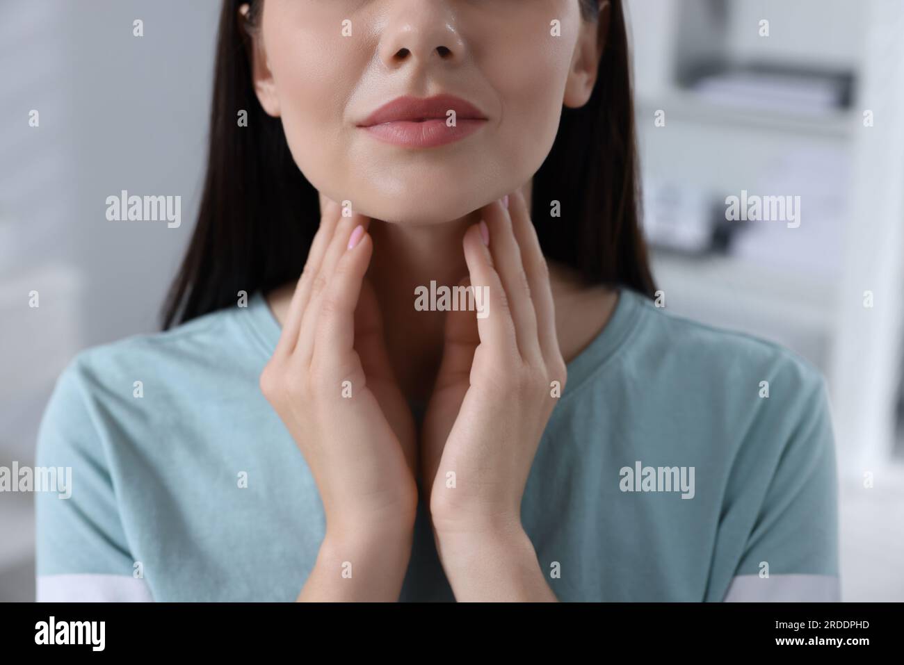 Endokrines System. Eine Frau, die die Schilddrüsen-Selbstuntersuchung drinnen macht, Nahaufnahme Stockfoto