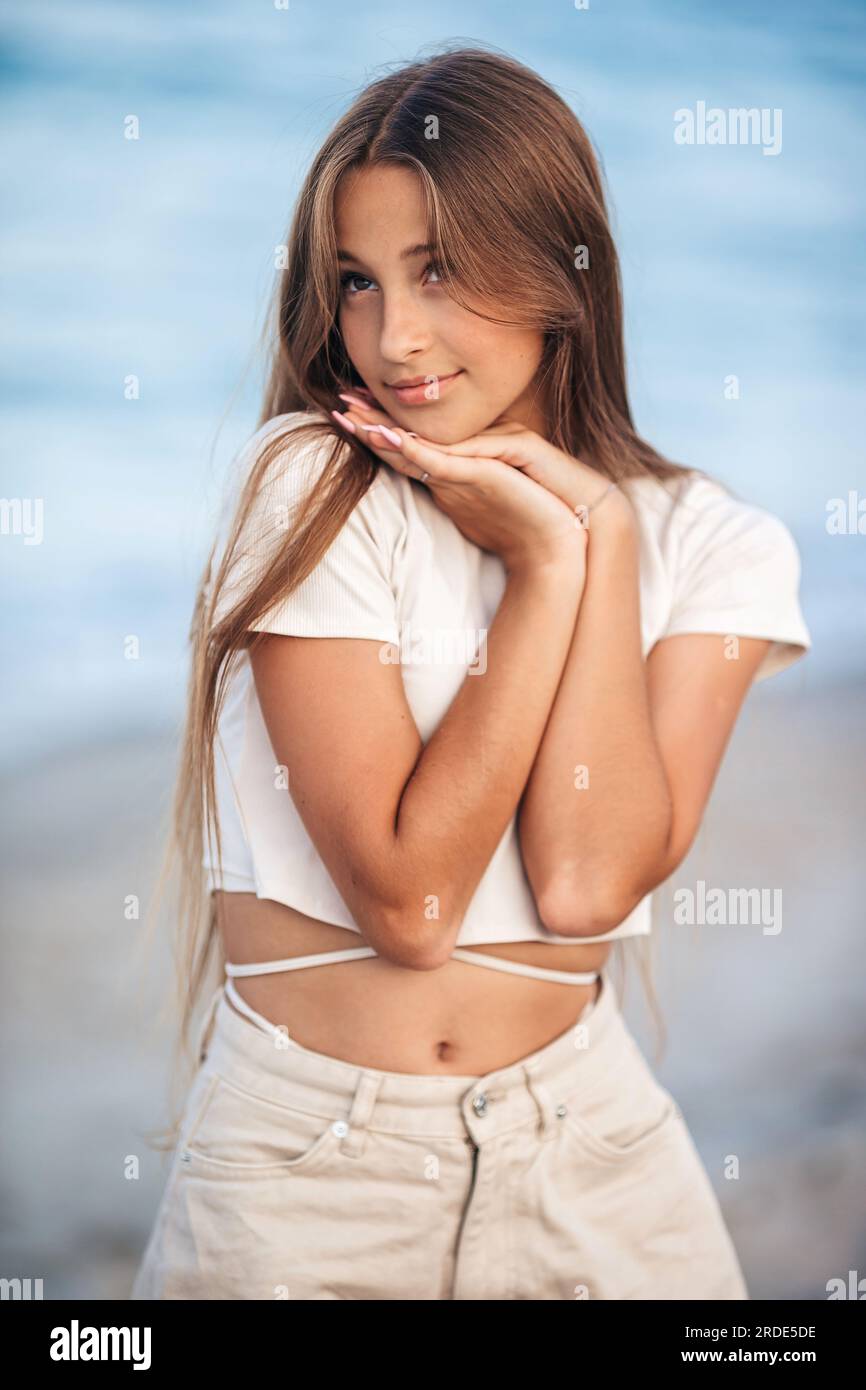 Süßes glückliches Mädchen am weißen Strand. Ein glückliches Mädchen im Hintergrund des Ozeans Stockfoto