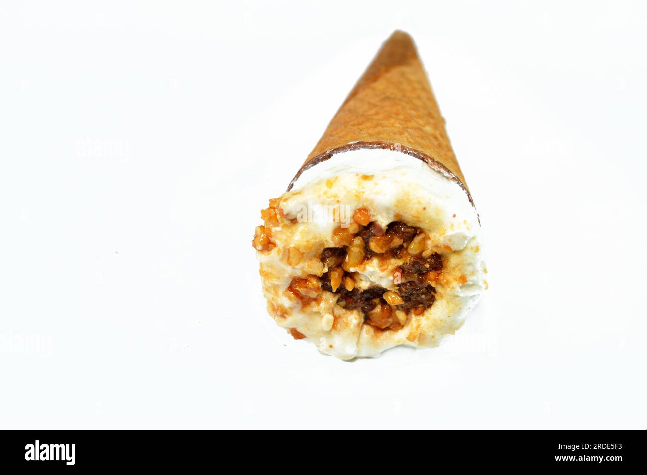 Eiscreme-Vanillekonus mit Schokoladenstückchen, Nüssen und Karamell in knusprigen Waffeln, selektiver Fokus des Schmelzens von kaltem Eis twi Stockfoto