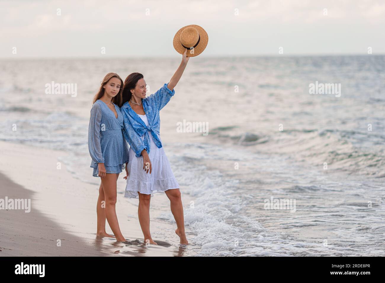 Familie der Mutter und ihrer Tochter, die am Strand spazieren gehen Stockfoto